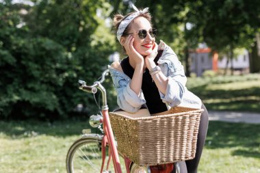 Portre genç, yetişkin, güzel bir kadın. Kırmızı antika bisikleti ve yeşil şehir parkı parlak güneşli yaz günü giysisi. Dışarıda bisiklete binen mutlu, güzel bir kadın. Sağlıklı yaşam tarzı.