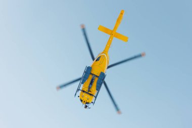 Manzaralı taban manzaralı modern sarı kurtarma helikopteri açık mavi gökyüzüne doğru uçuyor. Havacılık makinası siluet alp turizm servis ekibi.