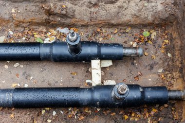 Yeni modern yalıtılmış kentsel boru hattı tesisatı inşaatı siperlerdeki yeraltı borularını ortaya çıkardı. Yalıtımlı çelik borular mühendislik altyapı geliştirme çalışmalarında yalan söylüyor.