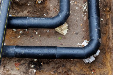 Yeni modern yalıtılmış kentsel boru hattı tesisatı inşaatı siperlerdeki yeraltı borularını ortaya çıkardı. Yalıtımlı çelik borular mühendislik altyapı geliştirme çalışmalarında yalan söylüyor.