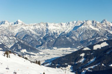 Manzaralı Saalbach-Hinterglemm-Leogang skicircus bölgesi karla kaplı dağlarla kaplı ufuk çizgisi keskin tepeler güneş ışığını aydınlattı. Vadi ormanları kayak pistleri, başkanlar kış tatili aktivitelerini beyaz yamaçlara taşıdı..