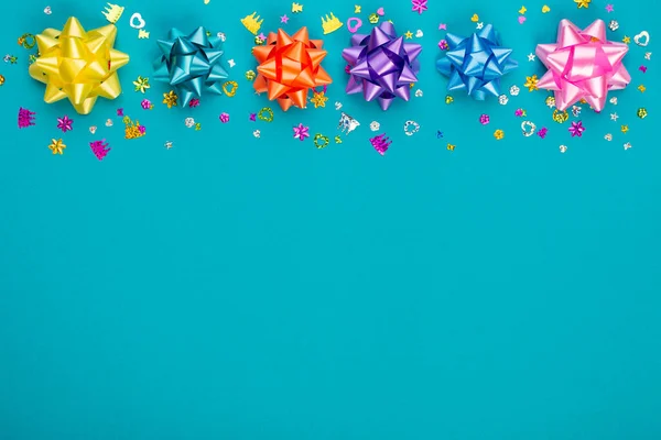 Blue background for birthday party with colorful stars and confetti. Present with copy space. Top view.