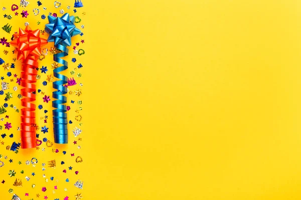 stock image Yellow background for birthday celebration with colorful serpentines and confetti. Present with copy space. Top view.