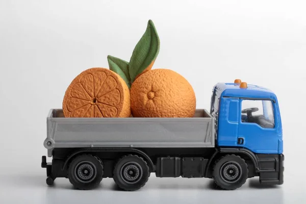 Orange fruits and a toy truck on a white background