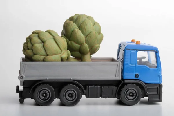 green artichokes and a toy truck on a white background