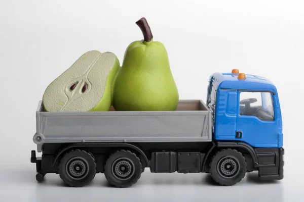 green pears and a toy truck on a white background