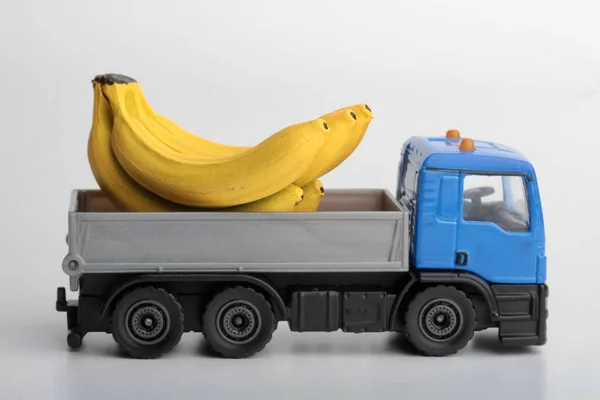 Yellow bananas and a toy truck on a white background