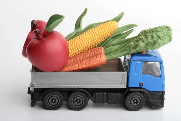 Toy truck carrying giant vegetables food for delivery service