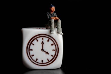 Siyah saat üzerinde minyatür bir adam.