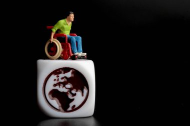 Tekerlekli sandalyedeki ve küredeki bir adamın minyatür figürü.