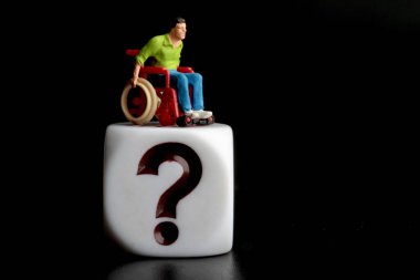 Tekerlekli sandalyede soru işareti olan küçük bir figür.