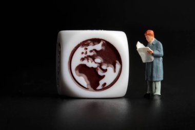 Gazetede uluslararası haberler okuyan bir adamın minyatür figürü. 