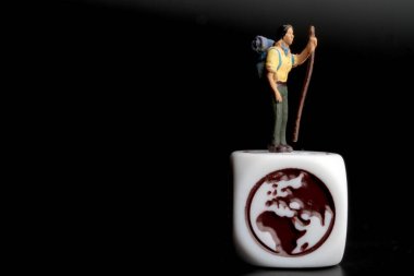 Dünya sembolünün tepesindeki bir yürüyüşçünün minyatür figürü