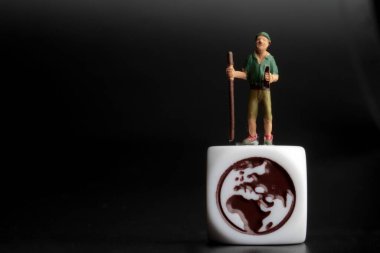 Dünya sembolünün tepesindeki bir yürüyüşçünün minyatür figürü