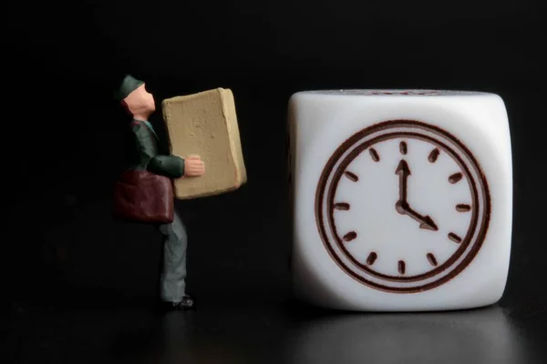 時計の記号のついた小包を持った配達人のミニチュアフィギュア — ストック写真