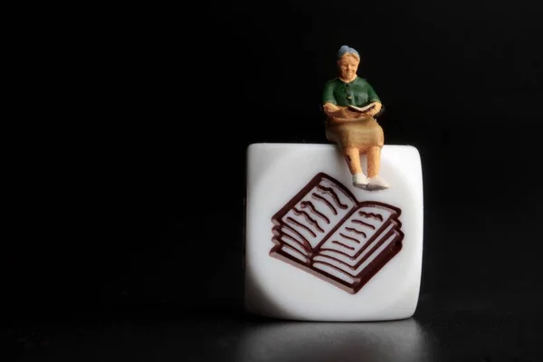 miniature figurine of people promoting books reading on a black background
