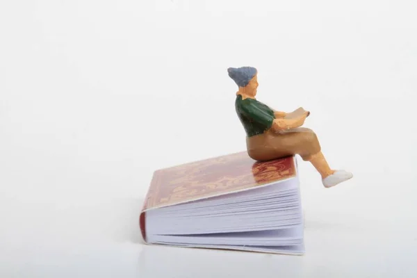 Miniaturowa Figurka Starszej Kobiety Siedzącej Gigantycznej Książce Czytającej — Zdjęcie stockowe