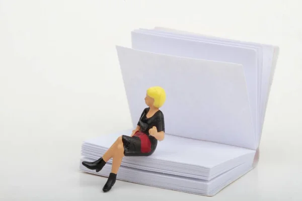 Μικροσκοπικό Ειδώλιο Γυναίκας Που Κάθεται Πάνω Μεγάλο Βιβλίο — Φωτογραφία Αρχείου