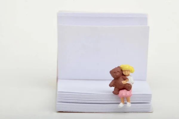 小さな女の子のミニチュア人形とテディベアが巨大な本の上に座っています — ストック写真