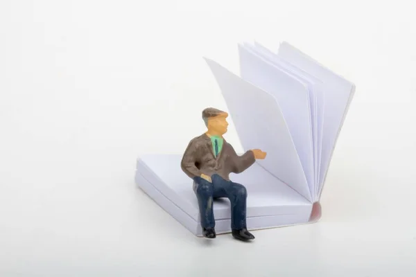 miniature figurine of an old man sitting inside a big paper book
