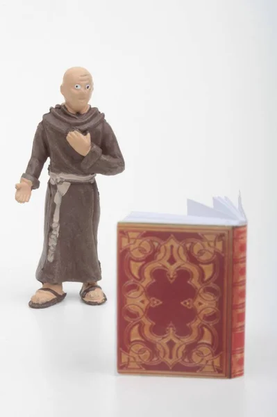 白い背景に古代の大きな本を持つ僧侶のミニチュアフィギュア — ストック写真