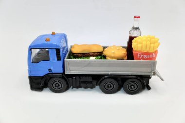 Patates kızartmalı burger ve teslimat için oyuncak kamyonda bir şişe bira.