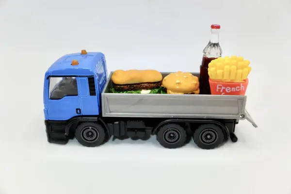 burger with french fries and a bottle of beer on a toy truck for delivery