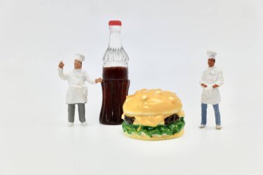 Bir şişe kola ve hamburgerle aşçıların minyatür figürleri.