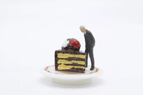 miniature figurine of a businessman checking a slice of chocolate cake