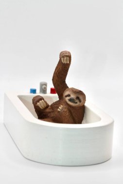 Küvette banyo yapan tembel bir hayvanın minyatür oyuncağı.