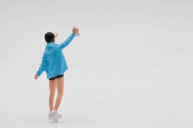 Beyaz duvarı sprey kutusuyla süsleyen küçük bir yazar kız figürü.