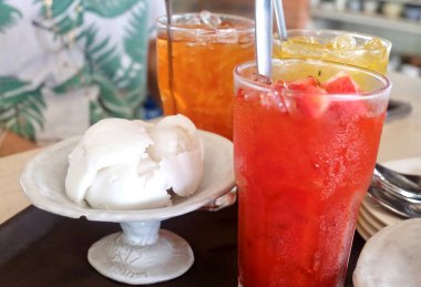 Delicious coconut ice cream is served alongside refreshing passionfruit punch, hibiscus tea, and lemon tea, creating a vibrant tropical dessert and beverage collection.