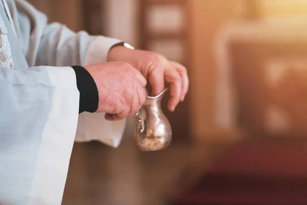 Close-up of Catholic priest hands consecrating the cross in the water