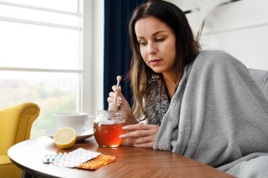 Hasta kadın çayına bal koyuyor.