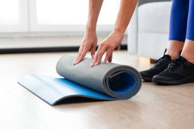 Yoga minderi katlayan kadın, ev konseptinde egzersiz.
