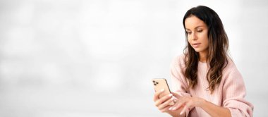 Çekici, güzel bir kadın akıllı telefon kullanıyor, evde çalışıyor.