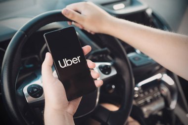 Wroclaw, Polonya - 25 AUG 2020: Uber sürücüsü akıllı telefonu arabada tutuyor. Uber ubran taşımacılığı için ekonomi hizmetini paylaşıyor.
