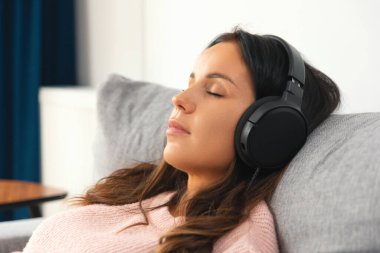Kulaklık takan, müzik dinleyen, rahatlayan bir kadın.