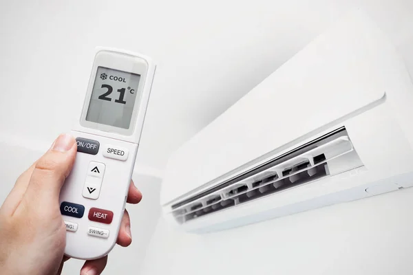 自宅でエアコン リモコン付きの手 空気の気候の概念 — ストック写真