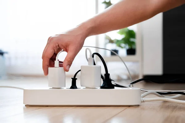 Hand holding electric plug, Multiple socket with connected plugs, energy efficiency