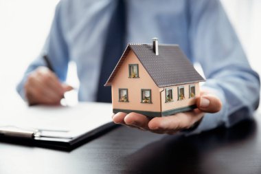 Emlakçı evi modelle temsil ediyor. Ev konsepti al ve sat