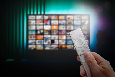 VOD servis ekranı. Adam elle uzaktan kumanda ile TV izlerken.