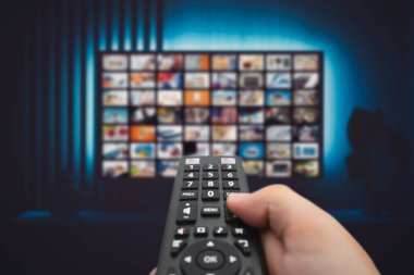 VOD servis ekranı. Adam elle uzaktan kumanda ile TV izlerken.