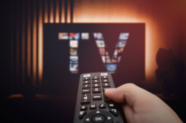 Akıllı televizyon, televizyon izliyor, uzaktan kumanda elinde.