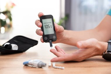 Şeker hastası kan testi yapıyor, glukometre kullanıyor.