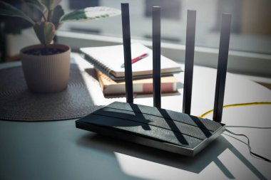 Modern wi-fi router on light table in room. High speed internet concept clipart