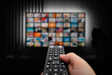 VOD servis ekranı. Adam elle uzaktan kumanda ile TV izlerken.