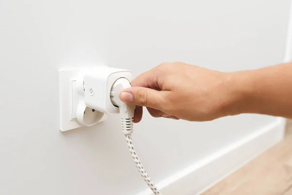 Man uses an electrical socket, smart plug into the socket. Control of electricity expenses