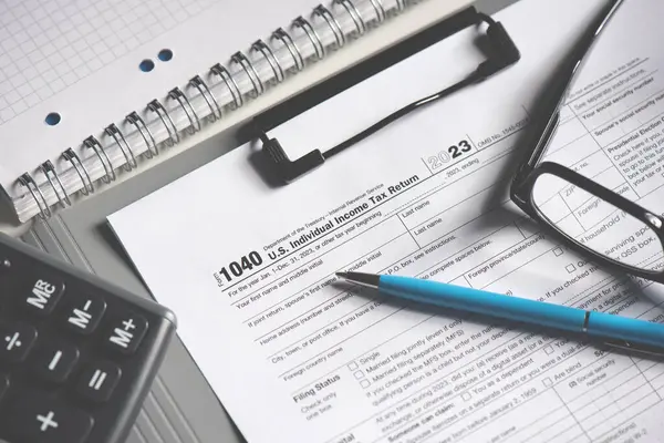 Hesap makineli vergi gelir kavramı, kalem ve vergi formu masanın üzerindedir