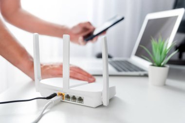 Modern Wi-Fi yönlendiricisini oturma odasındaki ışıklı masaya bağlayan kişi